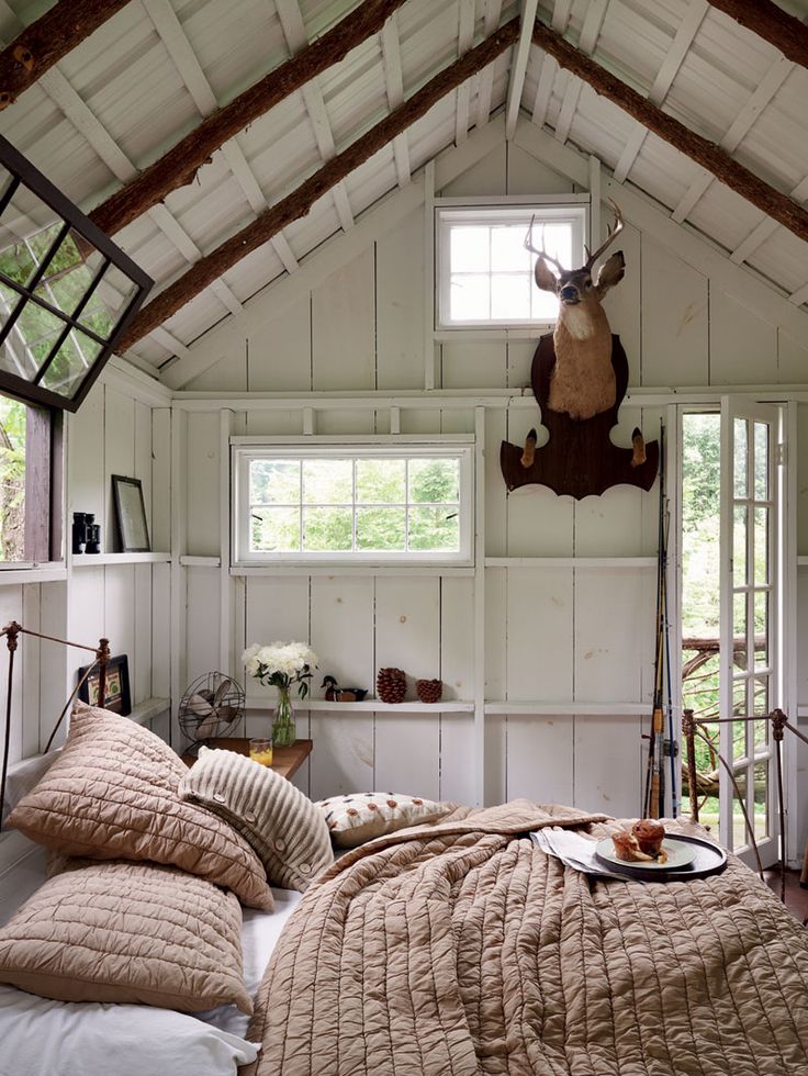 a bed sitting under a window in a bedroom next to a wooden floor and ceiling