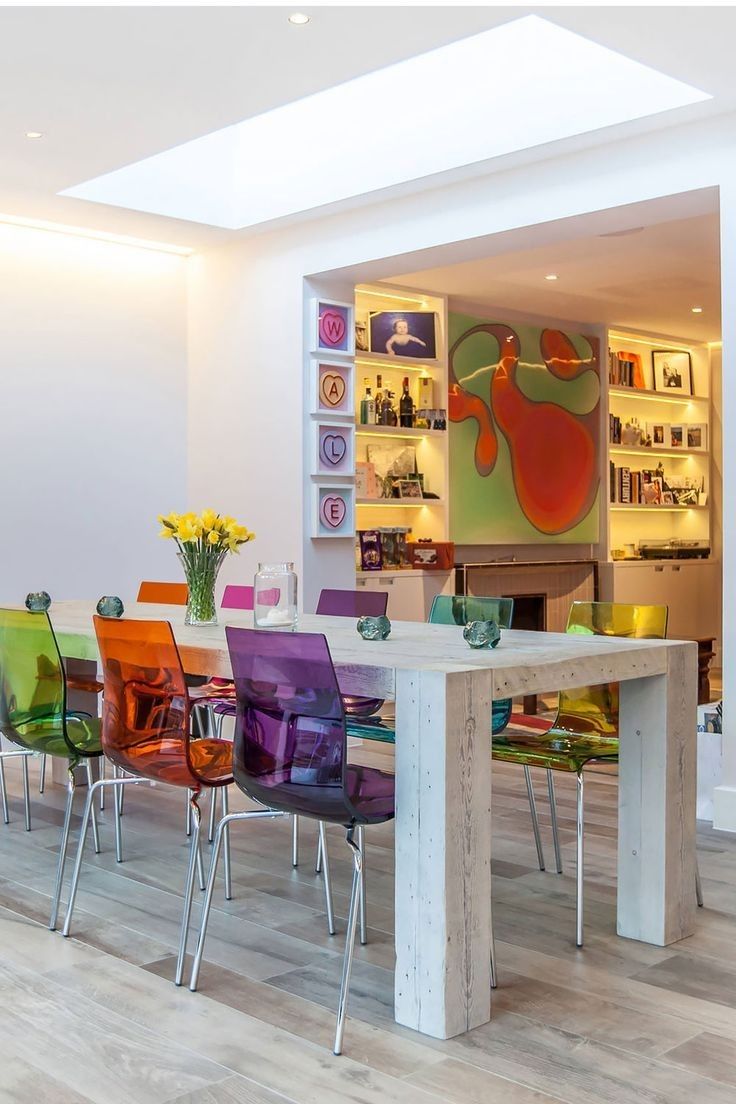 a dining room table with colorful chairs around it