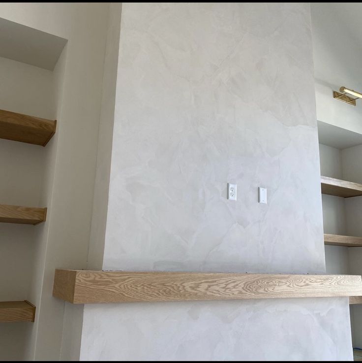 an empty room with some shelves and a light switch on the wall in front of it