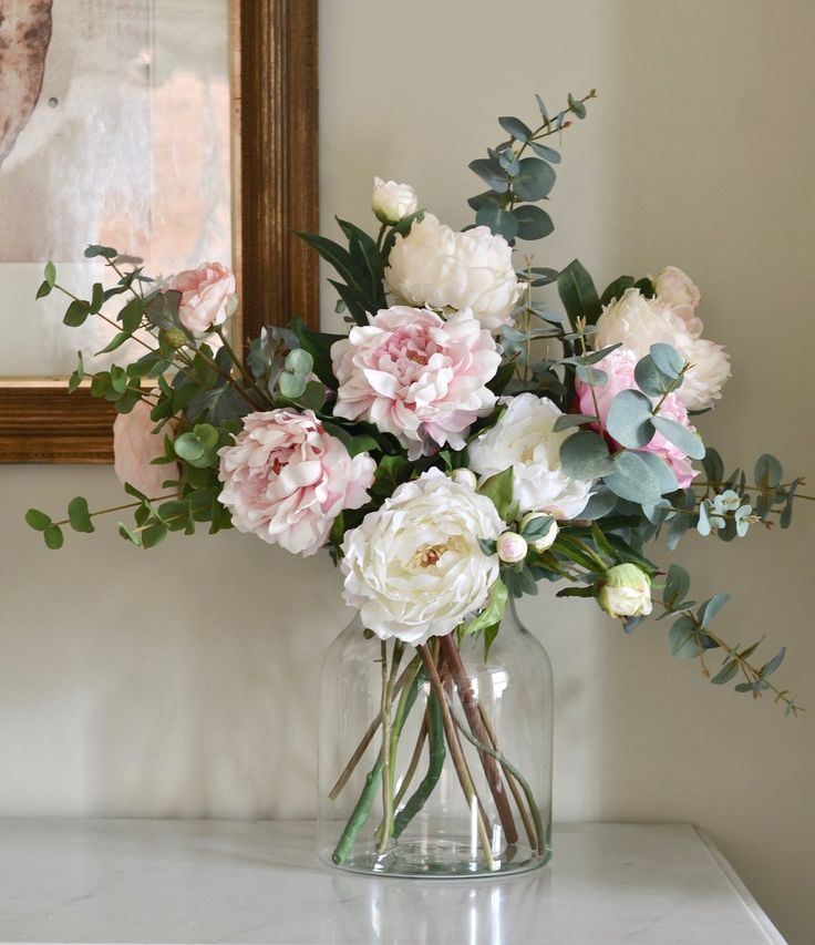 a vase filled with pink and white flowers on top of a table next to a mirror