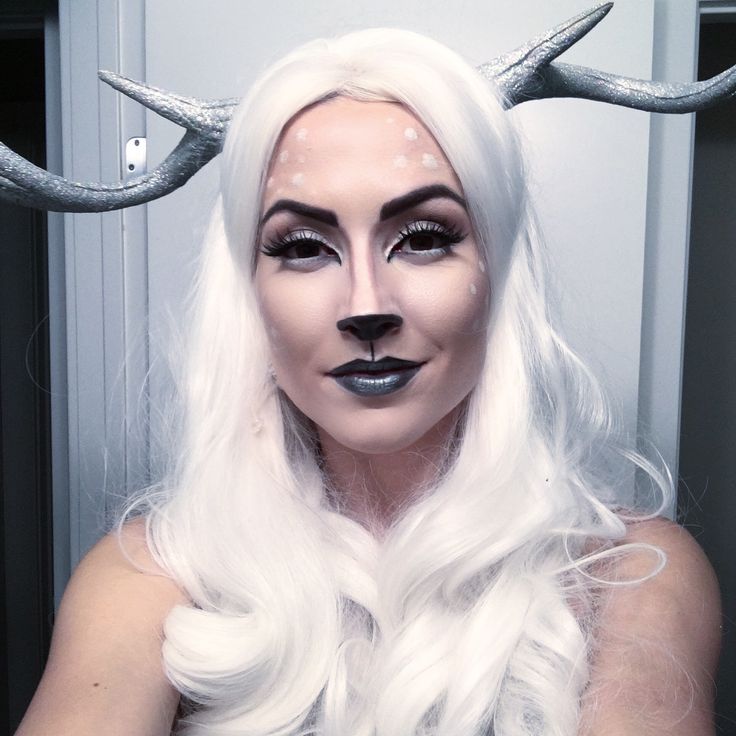 a woman with long white hair and horns on her head is posing for the camera