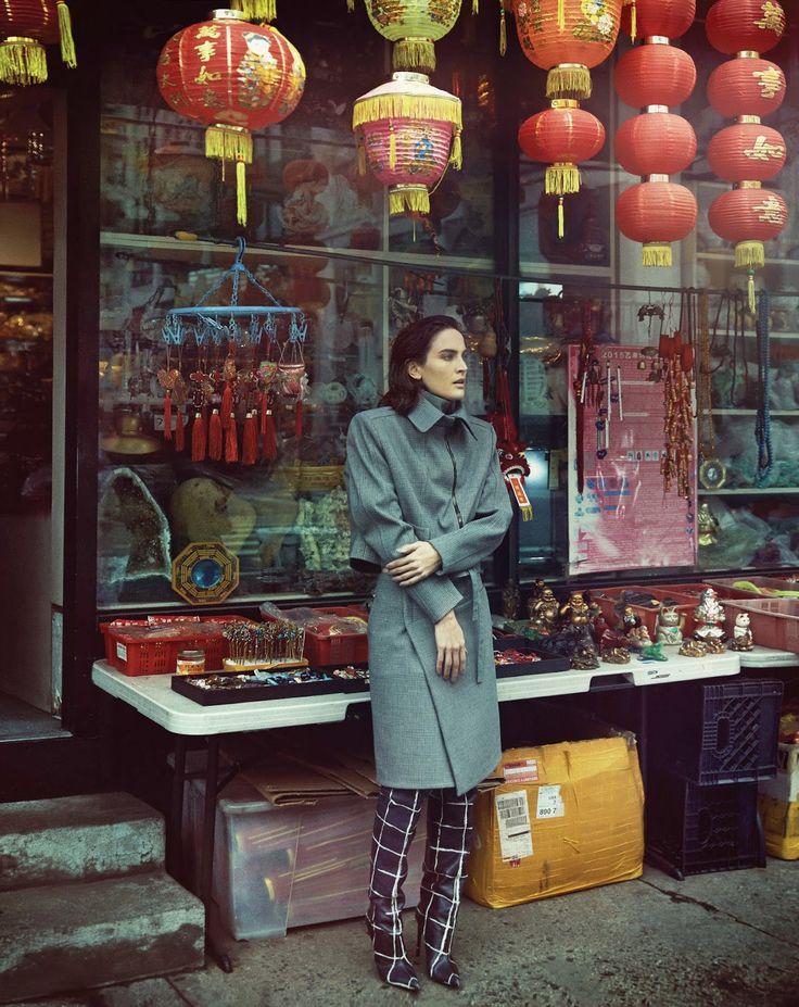 a woman standing in front of a store with red lanterns hanging from the ceiling and windows