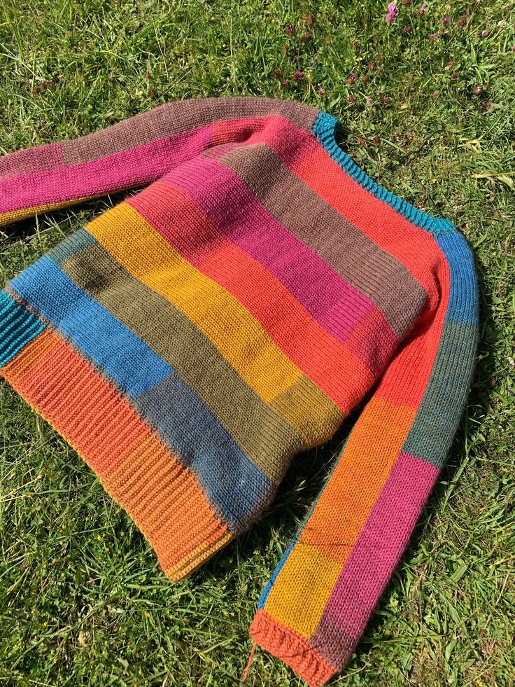 a multicolored sweater laying on the grass