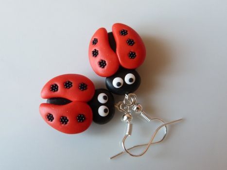 three red and black ladybug buttons with eyes attached to a pair of silver hooks