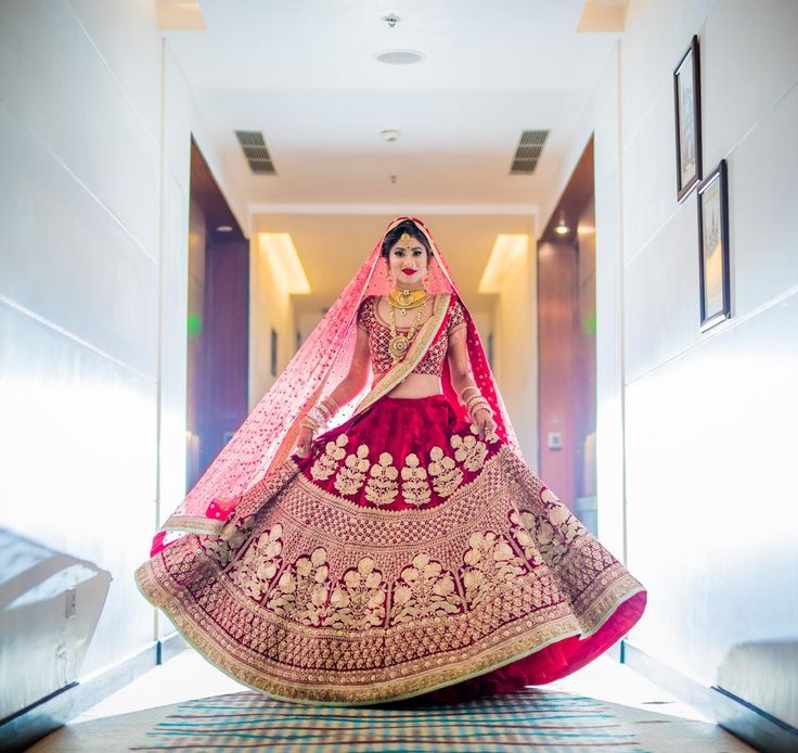 a woman in a red and gold bridal gown is standing on the floor with her arms behind her back