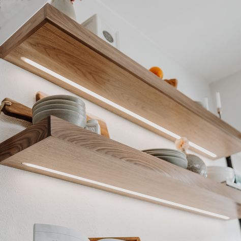 two wooden shelves with plates and bowls on them in a kitchen area that has white walls