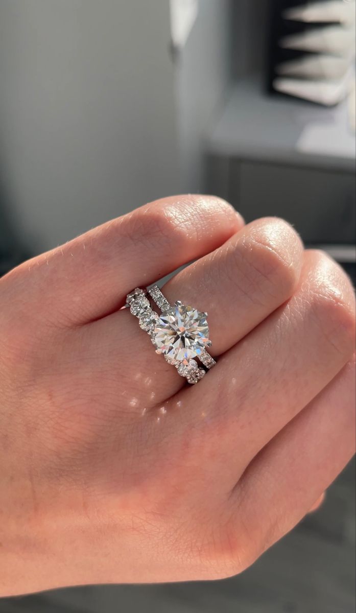 a woman's hand holding an engagement and wedding ring