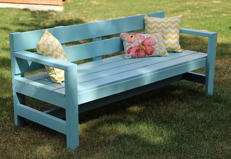 a blue bench with pillows on it in the grass