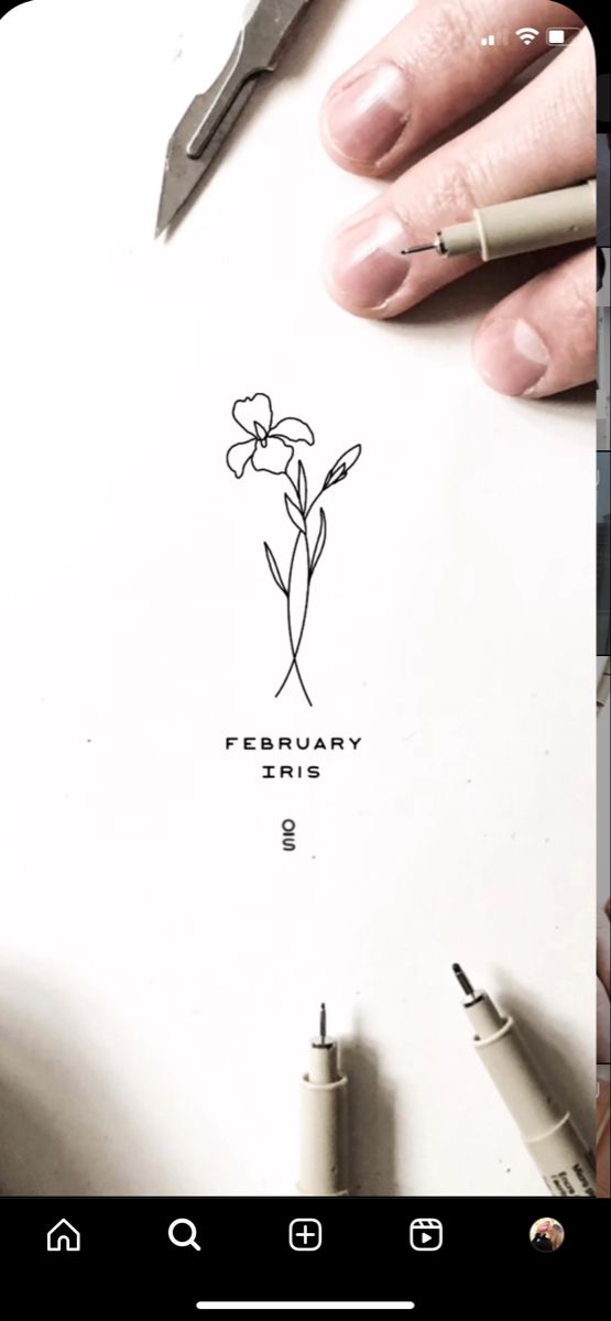 a person holding a pen and writing on a piece of paper with flowers drawn on it