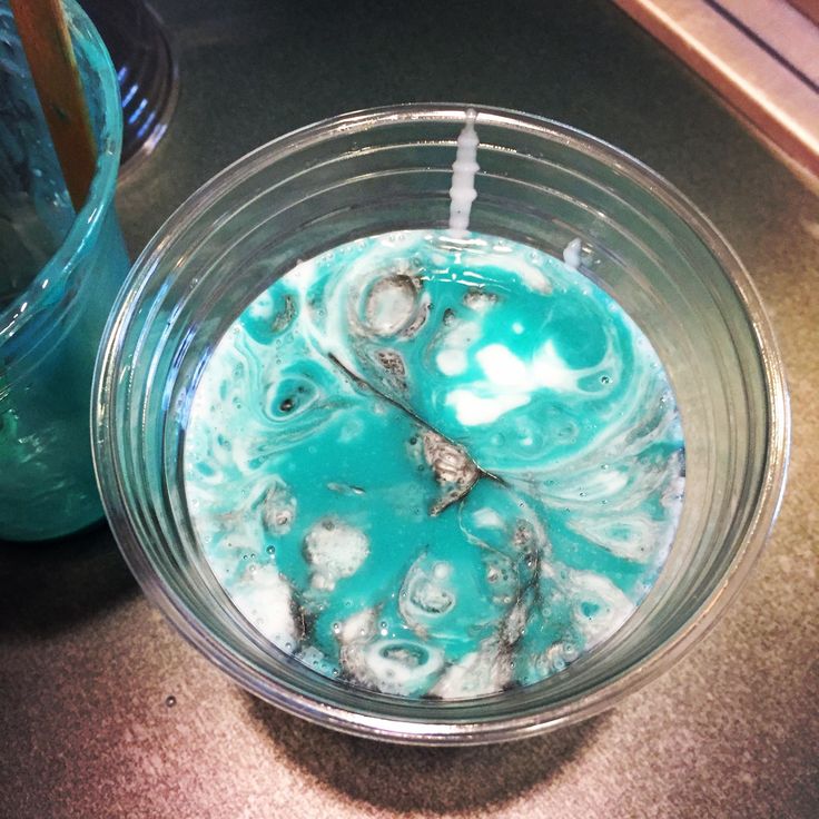 a glass bowl filled with liquid on top of a counter next to a blue vase