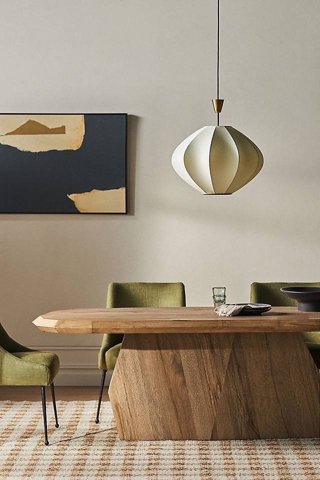 a dining room table with green chairs and an art piece on the wall behind it