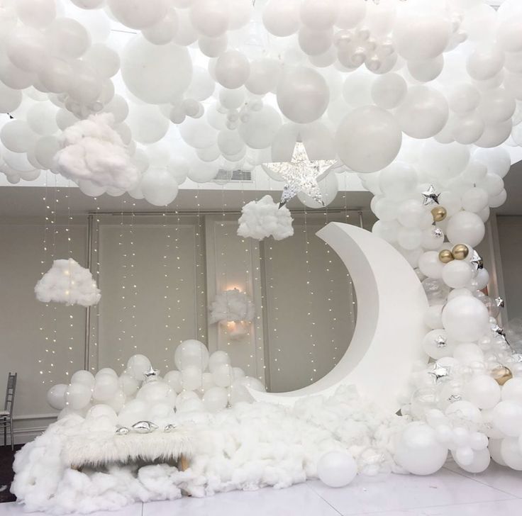 a room filled with white balloons and stars hanging from the ceiling over a crescent moon