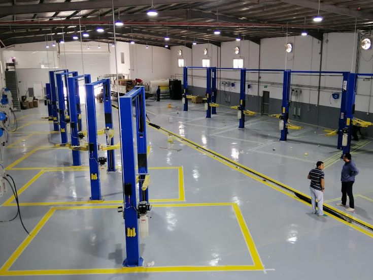 two people are walking through an empty warehouse with blue and yellow lines on the floor