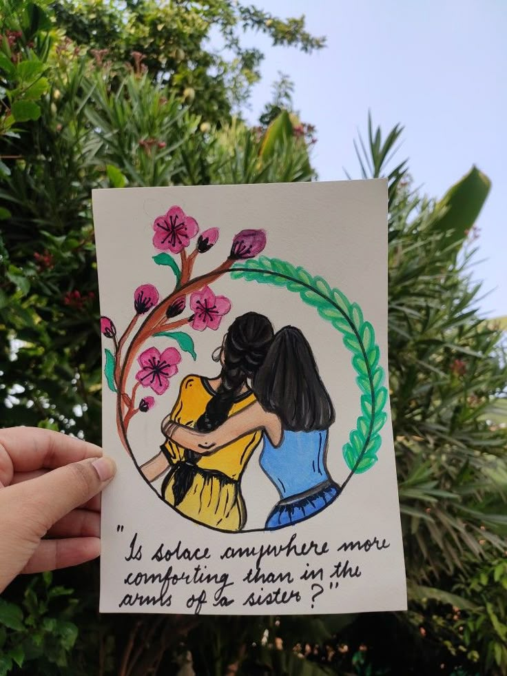 someone is holding up a card with an image of two women hugging each other in front of some trees