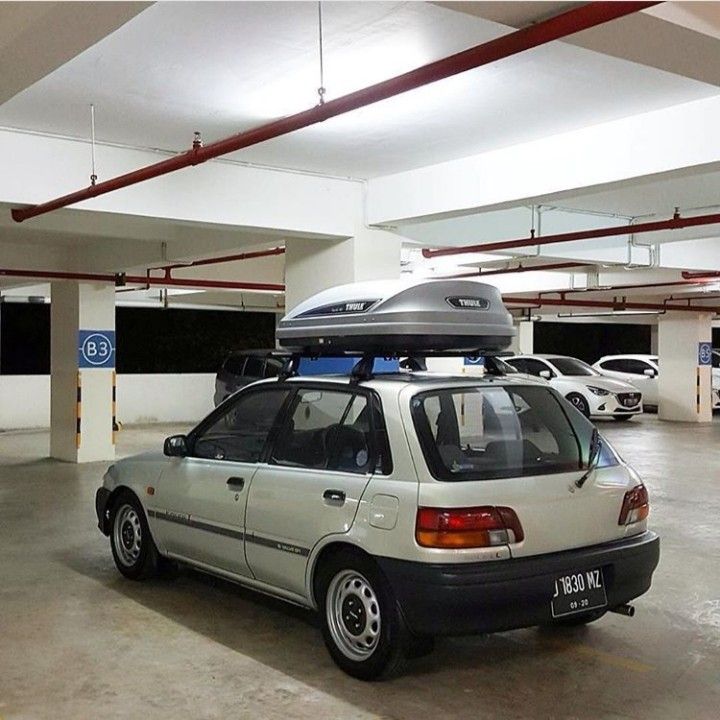 a white car parked in a parking garage with surfboards on top of the roof