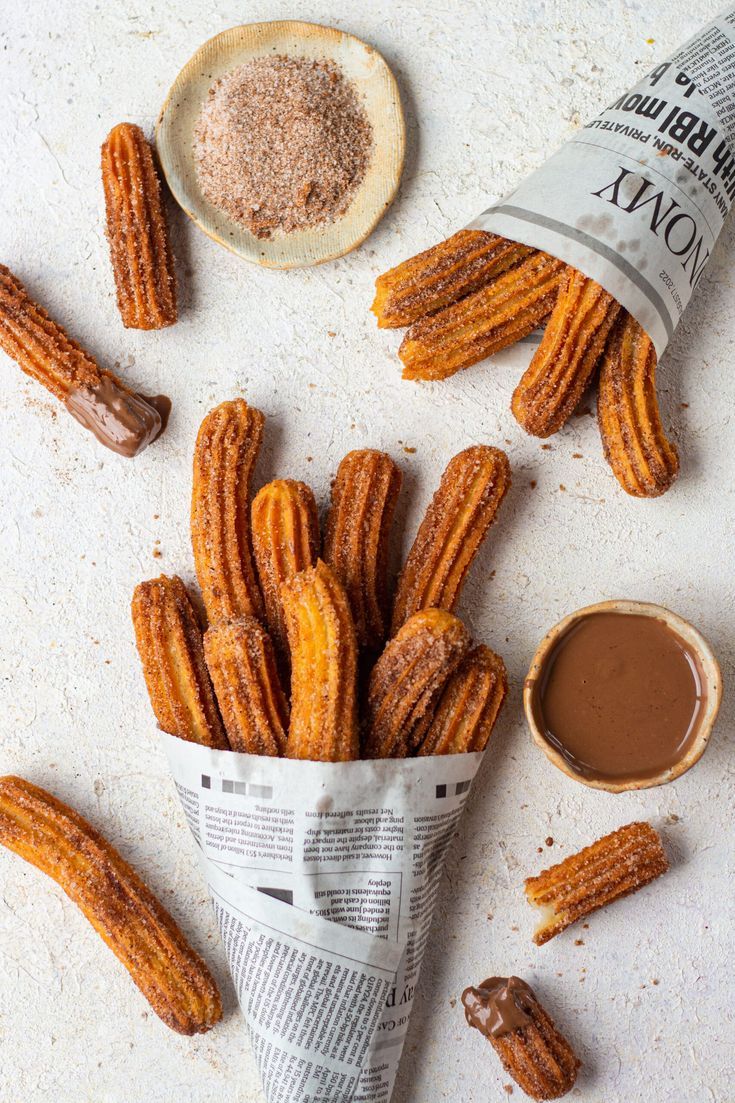 some churros are on the table next to a cup and sauce