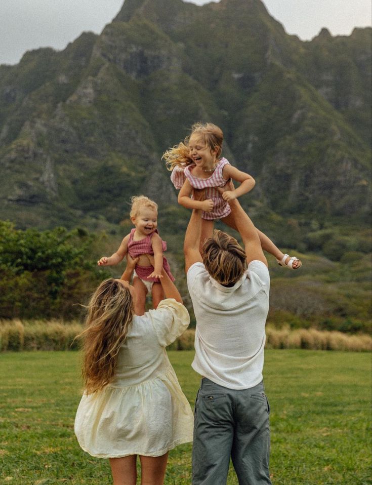 three people holding two small children in the air