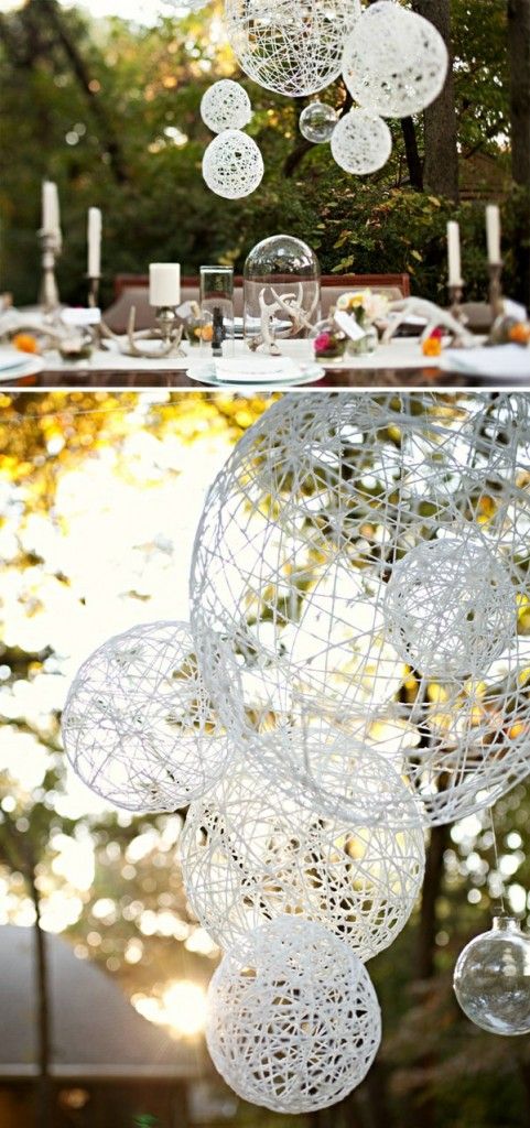 the table is set with white plates and silverware on it, and there are several hanging glass orbs