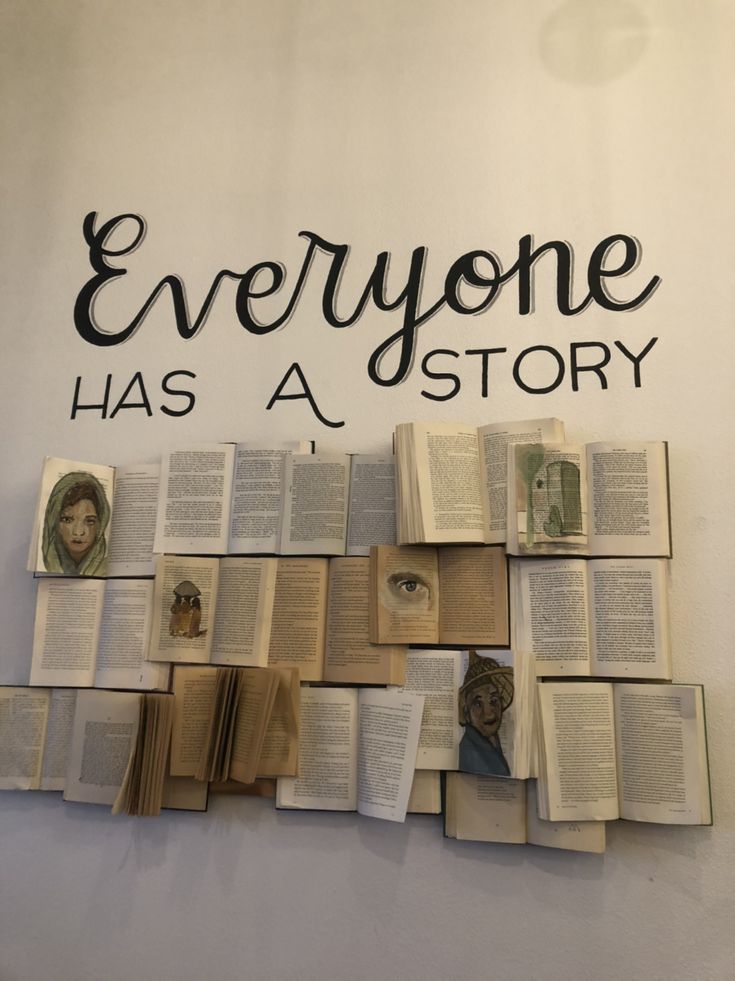 there is a sign that says everyone has a story with many books stacked on it