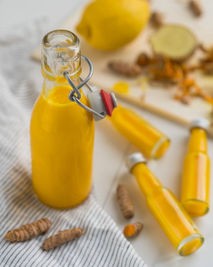 a glass bottle filled with yellow liquid next to some nuts