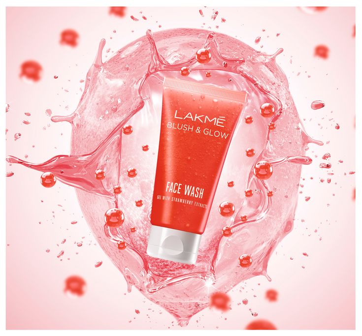 a tube of lakme bright and glow face wash on a pink background with water splashing around it