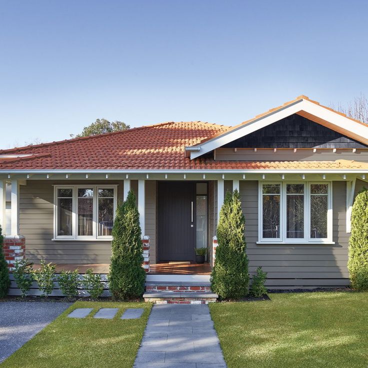 a small gray house with a red roof and white trim on the front door is shown