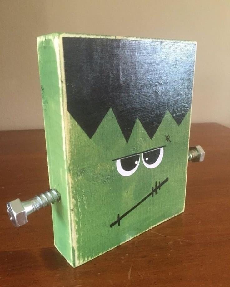 a wooden box with a green face and black hair on it sitting on a table