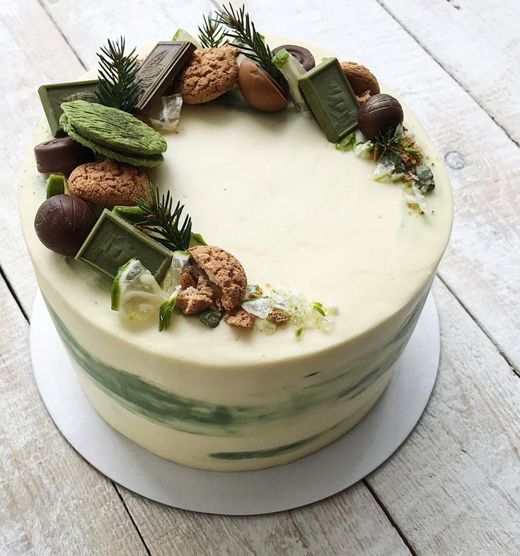 a cake with white frosting decorated with green and brown decorations on top of a wooden table