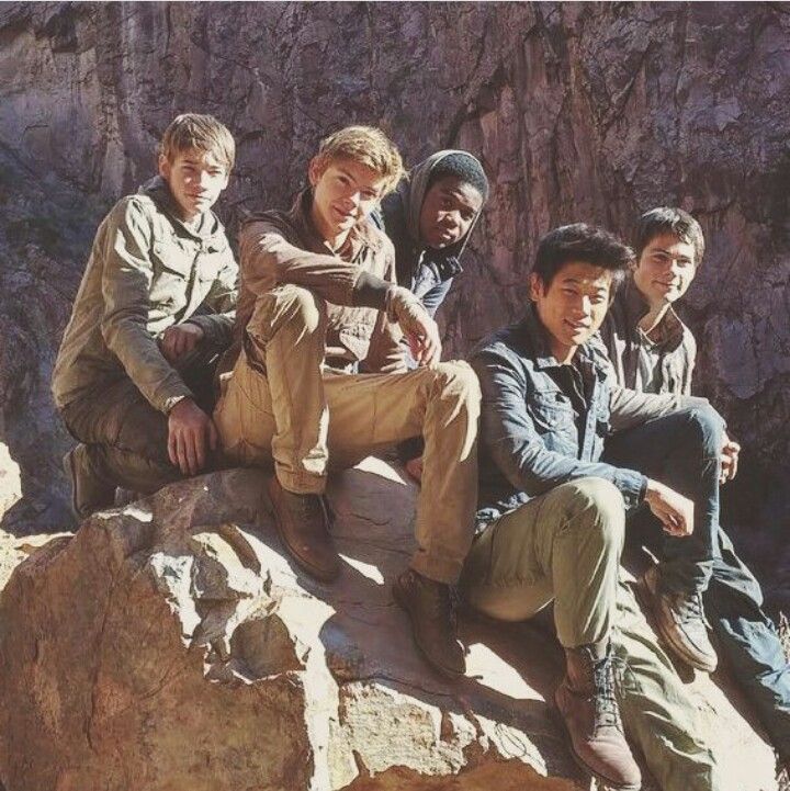 black and white photograph of four boys sitting on a rock in front of a mountain