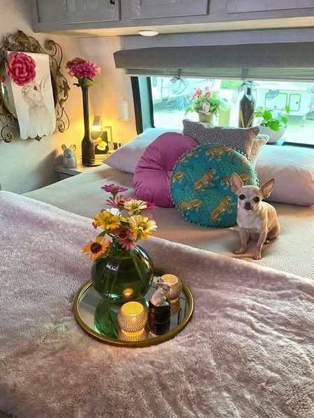 a small dog sitting on top of a bed next to a vase filled with flowers