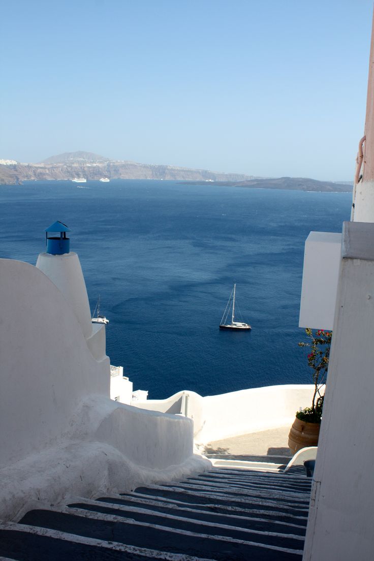 the stairs lead down to the water and boats are in the distance on the other side