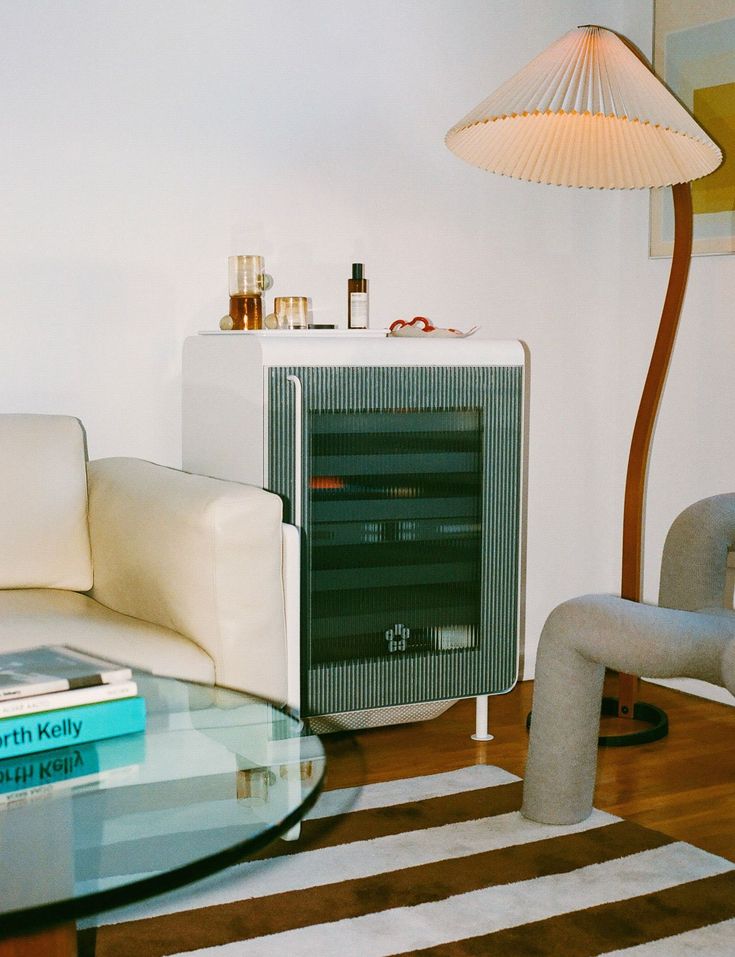 a living room with a couch, chair and computer tower on the floor in front of a lamp