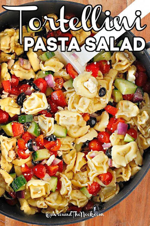 a skillet filled with pasta salad on top of a wooden table