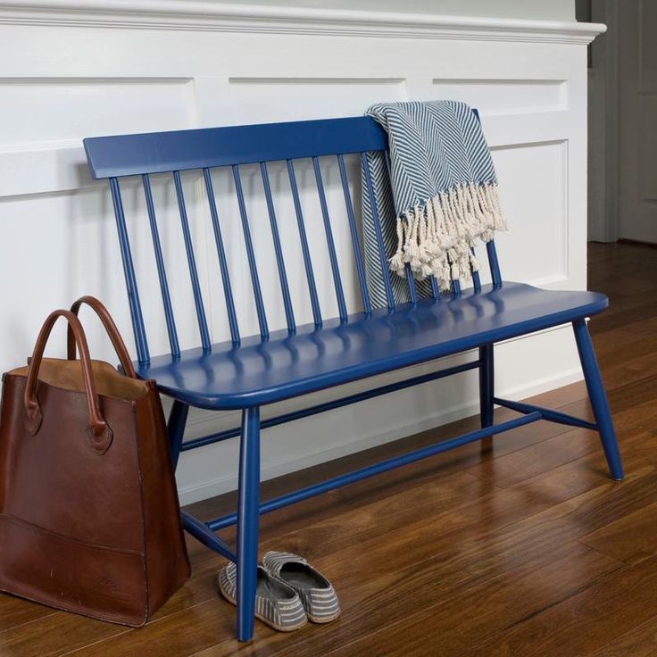 a blue bench sitting next to a brown purse on top of a hard wood floor