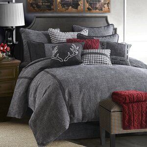 a bed with grey and red comforters in a bedroom