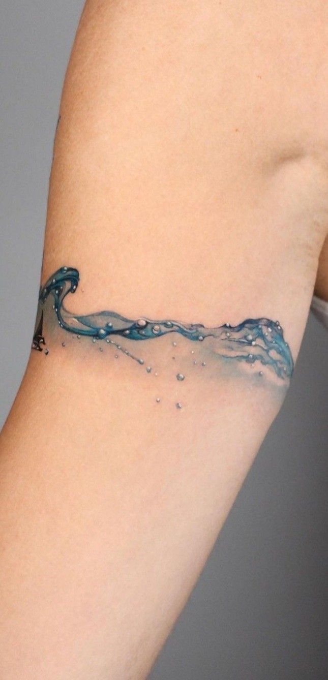 a woman's arm with a blue wave tattoo on the left side of her arm