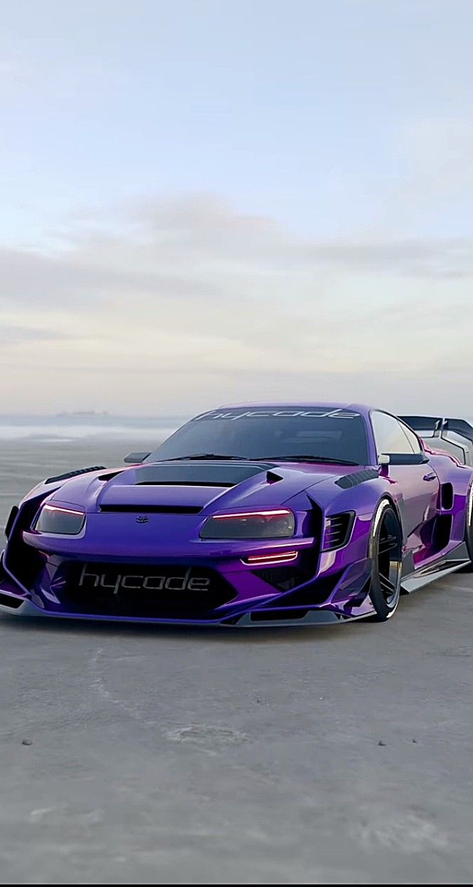 two sports cars parked on the beach next to each other in front of the ocean