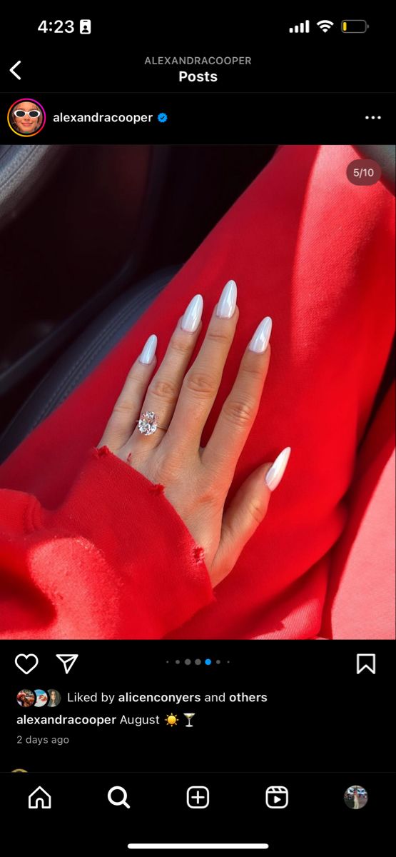 a woman's hand with white nail polish sitting in the passenger seat of a car