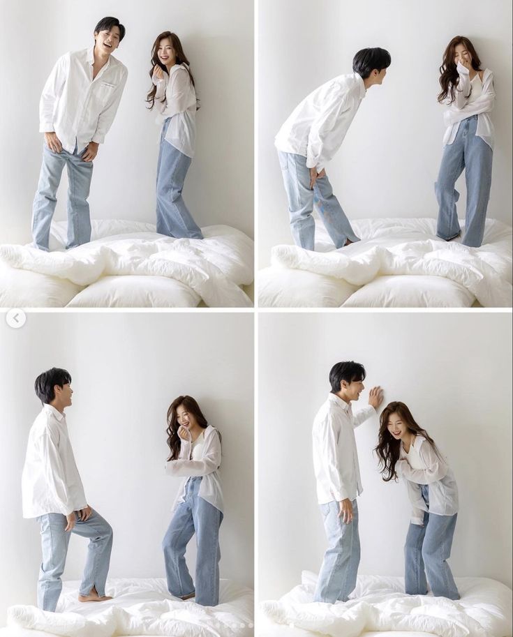 a man and woman standing on top of a bed next to each other in front of a white wall