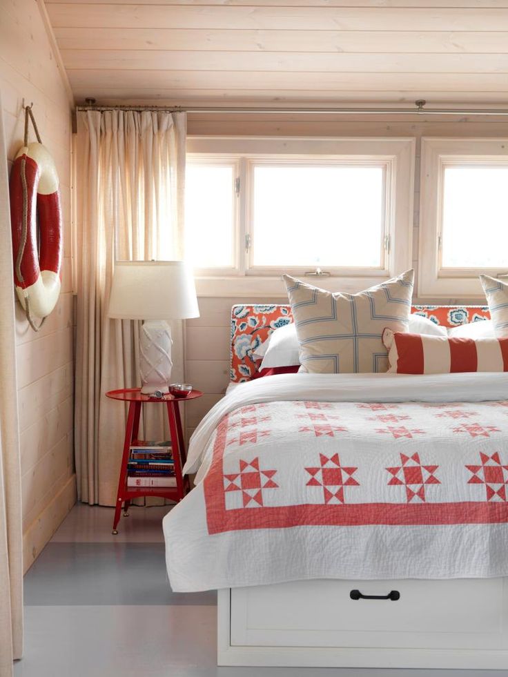 a bed with red and white quilts in a bedroom next to a window on the wall