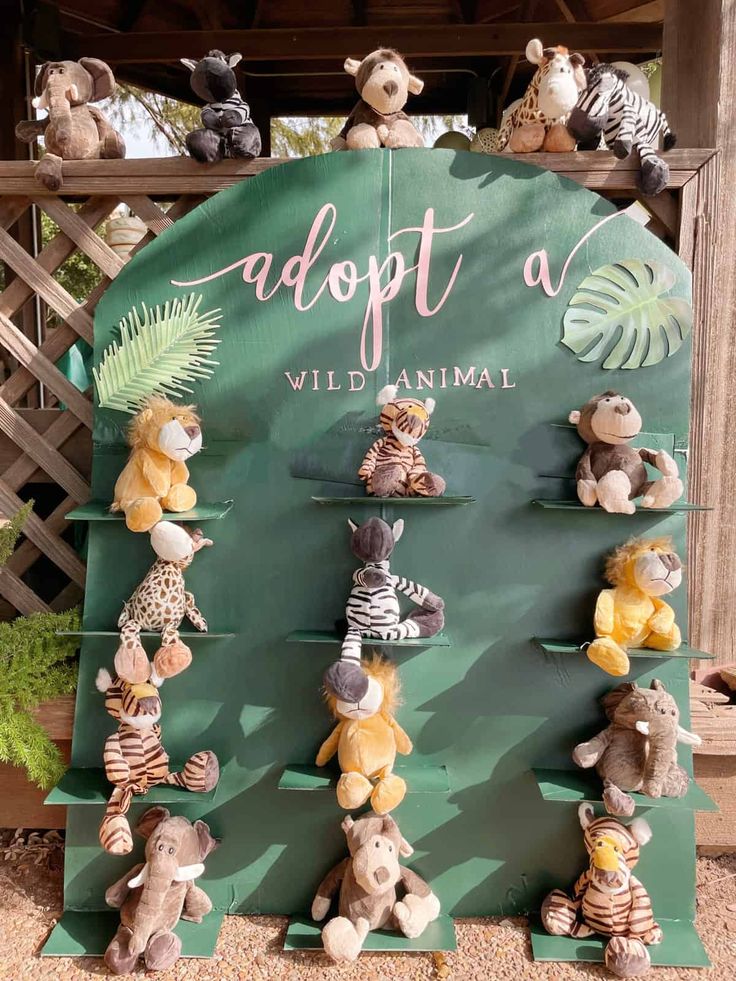 there are many stuffed animals hanging on the display rack in front of a sign that says adopt a wild animal