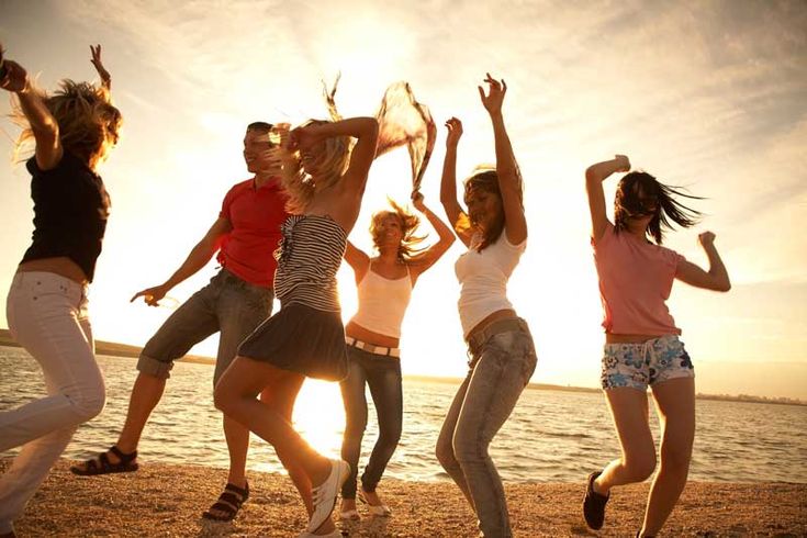 four young women jumping on the beach at sunset