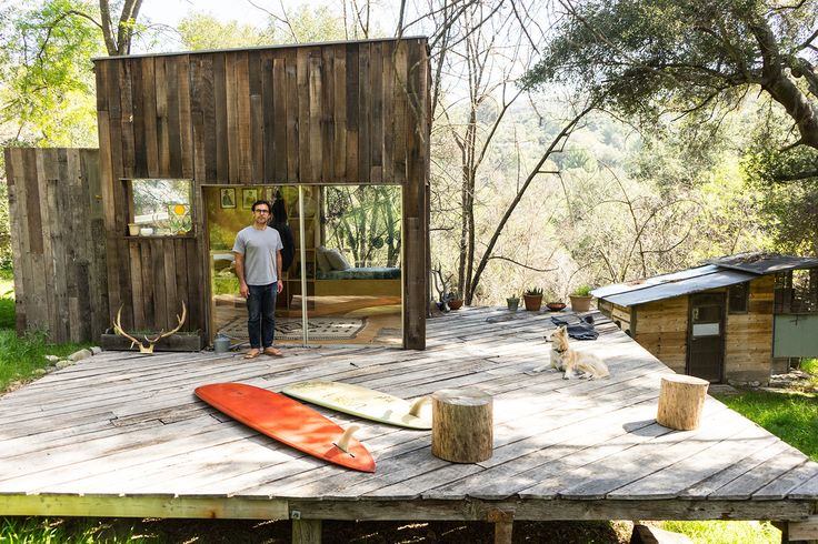 a man standing on top of a wooden deck next to a red surfboard