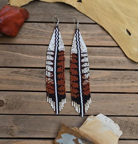 two brown and white beaded earrings sitting on top of a wooden table