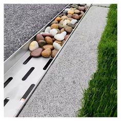 rocks are placed on the edge of a long metal rail that is next to grass