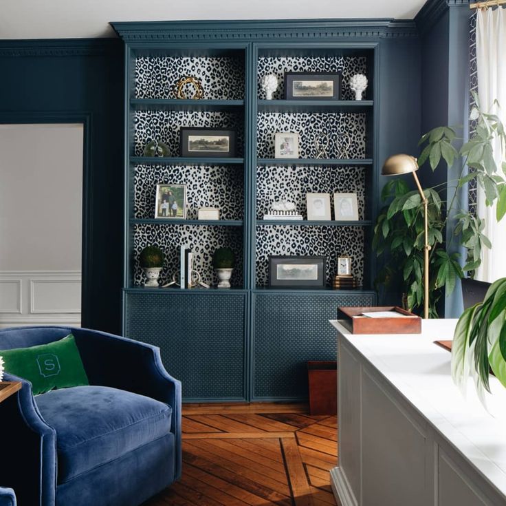 a living room filled with furniture and a blue chair in front of a book shelf