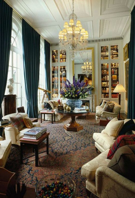 a living room filled with lots of furniture and a chandelier hanging from the ceiling