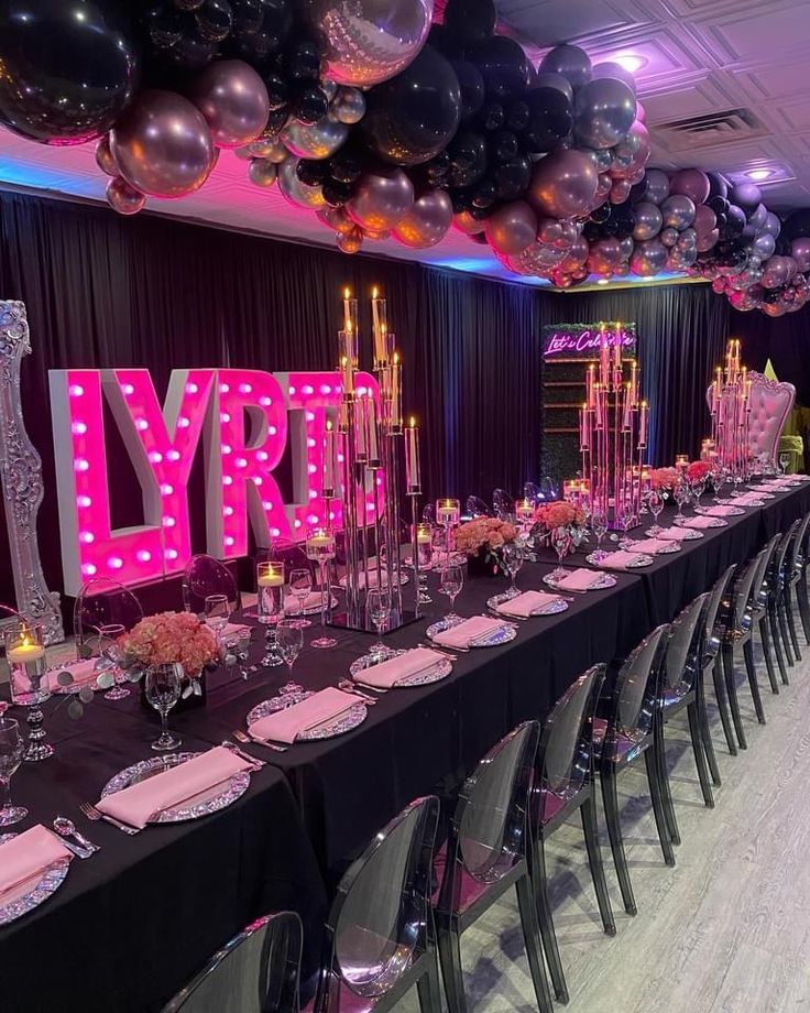 a long table is set up for a party with balloons and lights on the ceiling