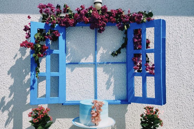 a cake sitting on top of a white table next to potted plants and flowers