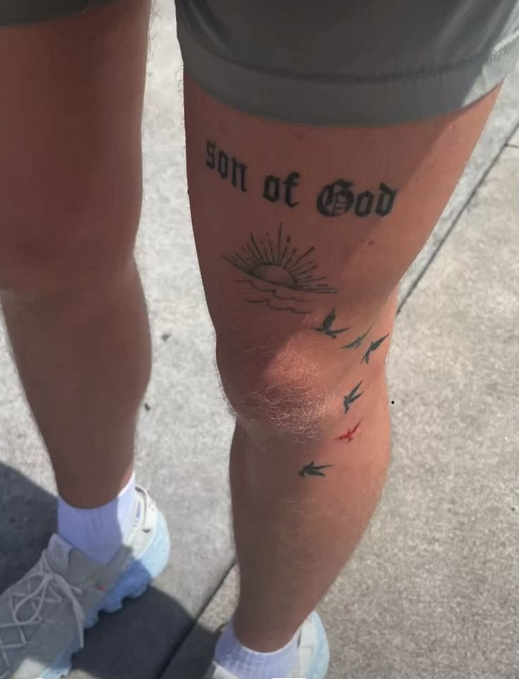 the legs and ankles of a person with tattoos on them, standing in front of a sidewalk